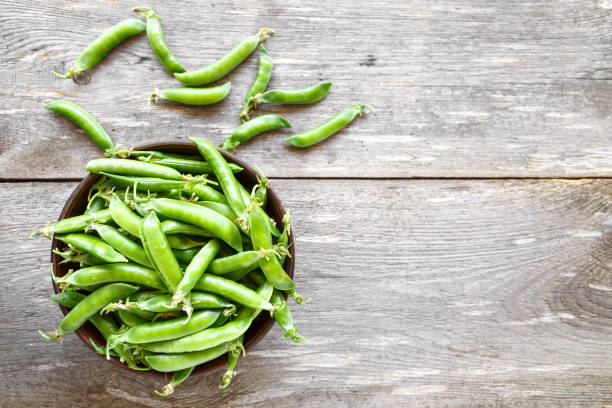istock Green peas in a clay plate on a wooden table. 947259670
