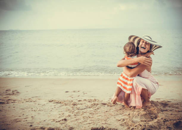 Mutter und Tochter umarmt am Strand – Foto