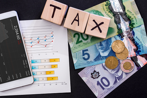 Taxation concept with canadian dollar, business graph and phone