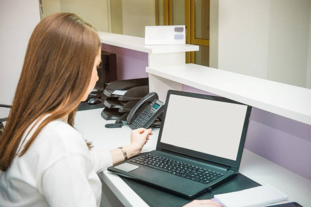 istock Backview administrative manager working on laptop computer in office behind the reception desk. Administrator in the office, clinic, center, hotel. Occupation concept. Selective focus, space for text. 947264268