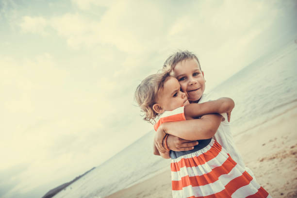 Rear view of family enjoying summer vacations on beach, holding hands and having fun.