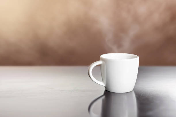 istock white ceramic hot coffee cup on wooden table with steam 947275770