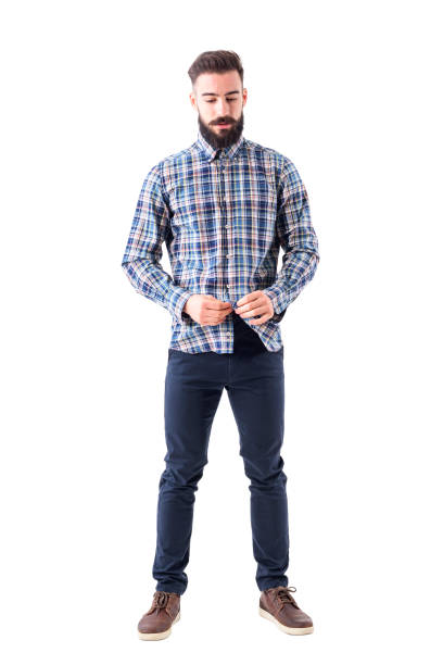 istock Relaxed cool bearded hipster buttoning plaid checkered shirt looking down. 947279506
