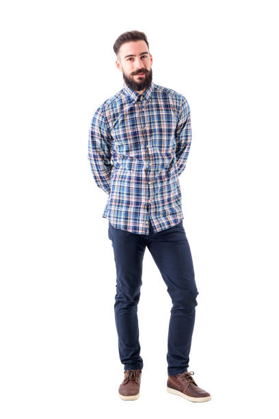 istock Smiling young bearded man biting lips and looking at camera with hands behind back 947279662