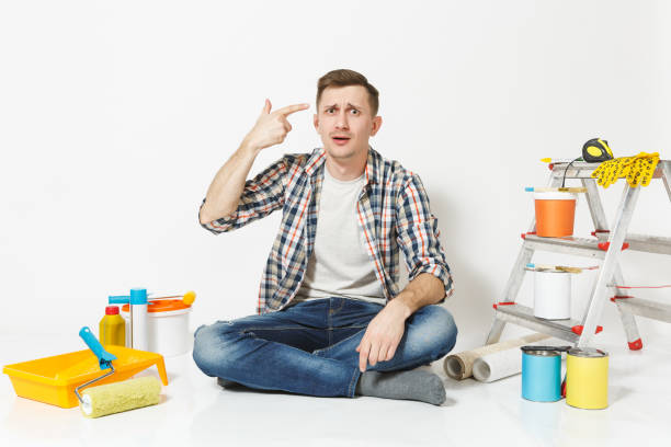 istock Confused shocked man point fingers to head as if he about shoot himself. Instruments for renovation apartment isolated on white background. Wallpaper, gluing accessories, tools. Repair home concept. 947290230