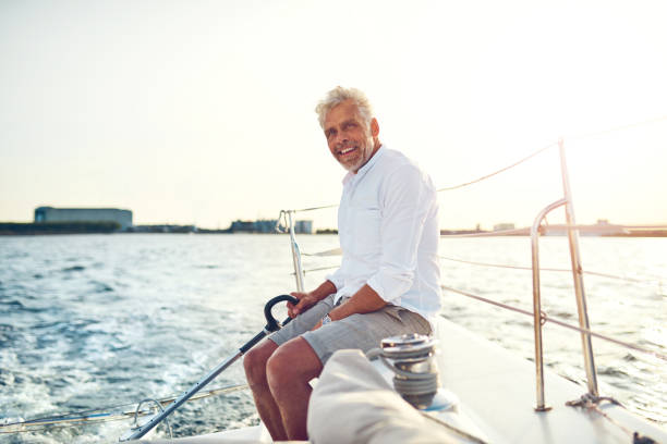 istock Smiling mature man sailing his boat along the coast 947294982
