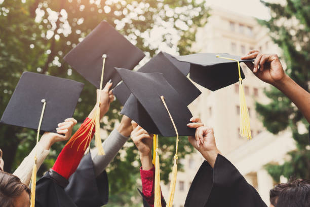 un groupe de diplômés jetant des casquettes de graduation dans l’air - université photos et images de collection