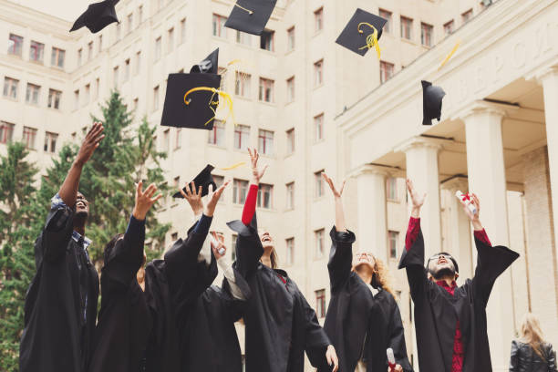 istock A group of graduates throwing graduation caps in the air 947295172