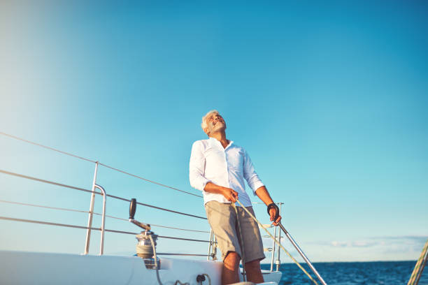 istock Mature man looking skyward while out sailing on his boat 947295812