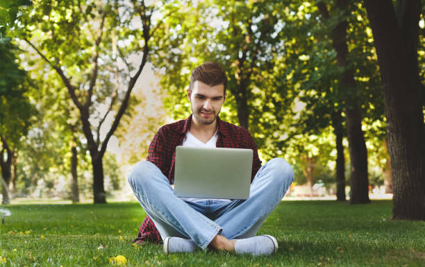istock Handsome young man using a laptop outdoors 947300078