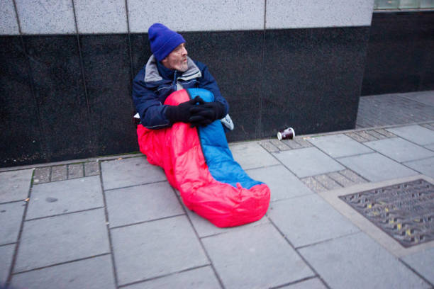 One man, young homeless man holding acoustic guitar, walking away, rear view.