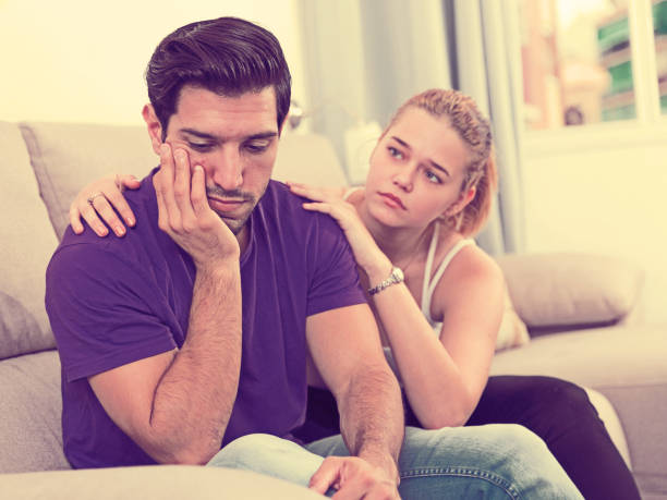 istock Ggirl comforting upset boyfriend on sofa 947304210