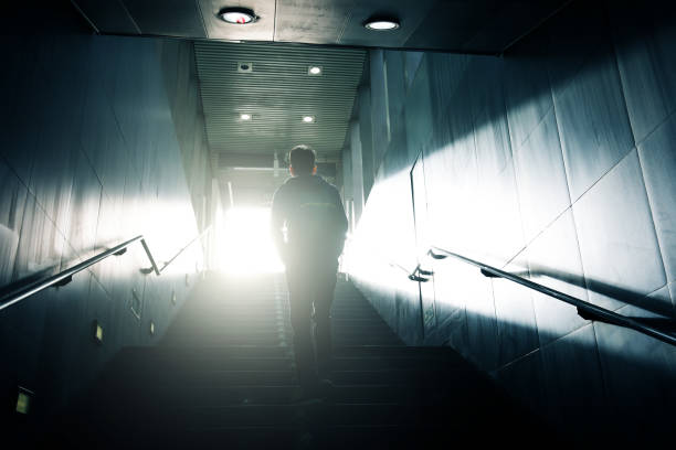 istock Man walking up to sunlight in dark passageway 947307408