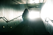 Woman walking to light in dark stairs