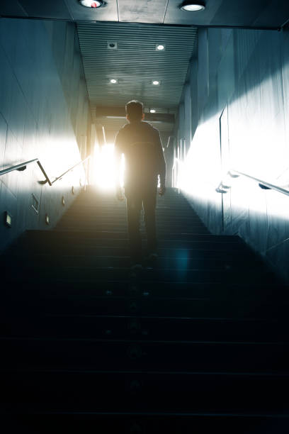 istock Man walking up to sunlight in dark passageway 947307466