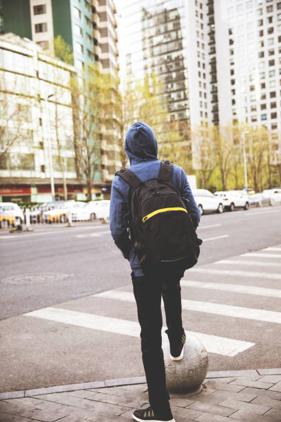 istock Man with a backpack standing on the city street 947308120