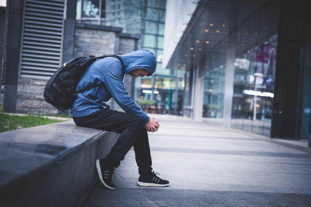 hombre triste sentado en la calle de la ciudad - unemployment fotografías e imágenes de stock