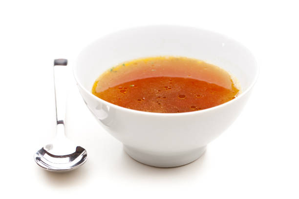 Clear broth with spoons next to it stock photo