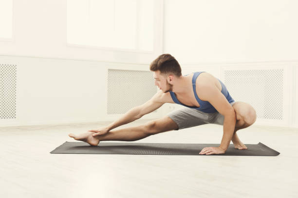 istock Man stretching at white background indoors 947314248