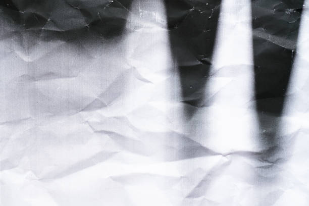 Detailed view of crumpled white paper with visible creases and soft wrinkles creating a dynamic, uneven surface. The light grey tones and rough texture suggest imperfection and spontaneity.