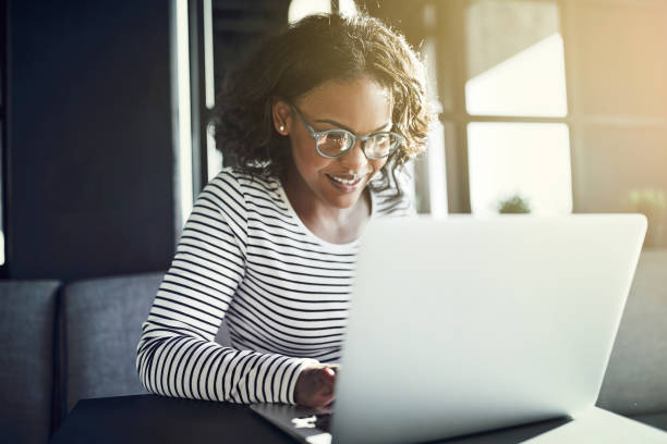 istock Smiling African woman working on her laptop at a table 947316138