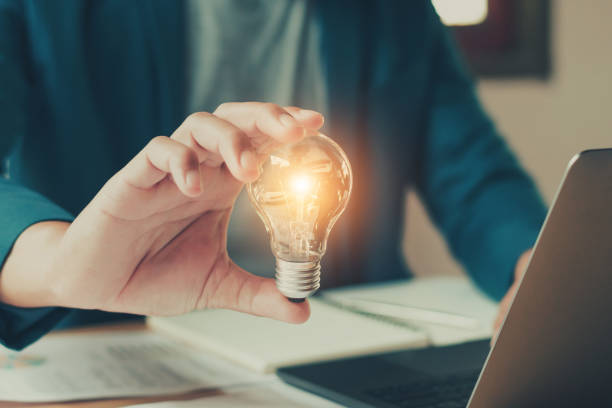 istock businessman hand holding lightbulb with using laptop.concept saving energy 947316152