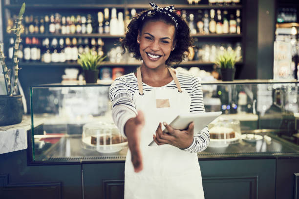 Smiling African entrepreneur offering a handshake in her cafe