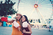 Women at the amusement park eating pink cotton candy and taking selfie/vlogging