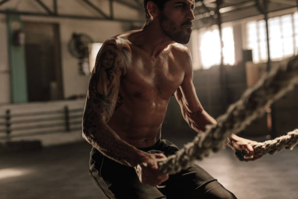 istock Powerful man exercising with battle ropes at gym 947319082