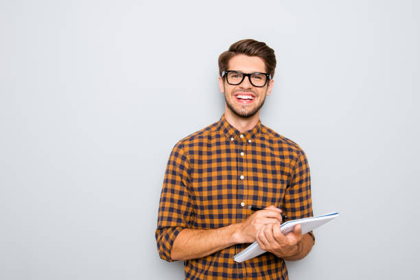 Happy young smart student in glasses writing in notebook