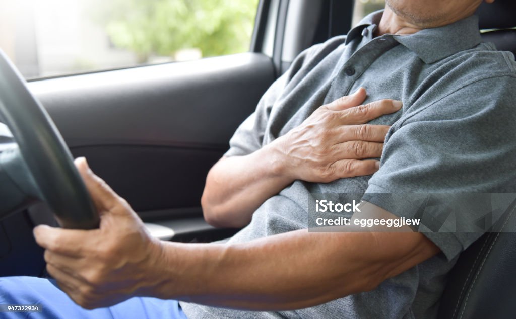 Asian Senior man having heart attack. Asian Senior man having chest pain from heart attack while driving a car.  Illness, exhausted, disease. Driving Stock Photo