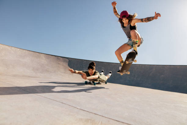 istock Female skaters doing stunts at skate park 947323064