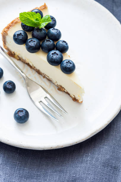 istock Piece of cheesecake with fresh blueberries on white plate 947324094