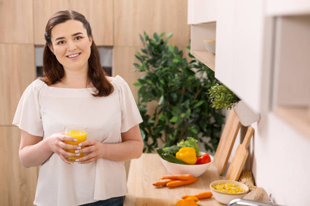 istock Pleased pretty woman drinking orange juice 947324184