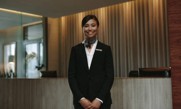 Female hotel receptionist ready to greet guest Young smiling female receptionist at the hotel front desk ready to greet guest. Female concierge looking at camera and smiling. concierge photos stock pictures, royalty-free photos & images