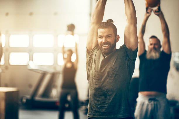istock Smiling young man swinging weights during a gym exercise class 947327498