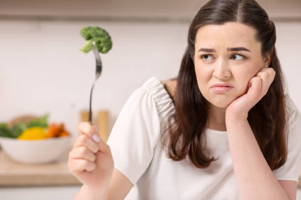 istock Annoyed bleak woman eating broccoli 947331988