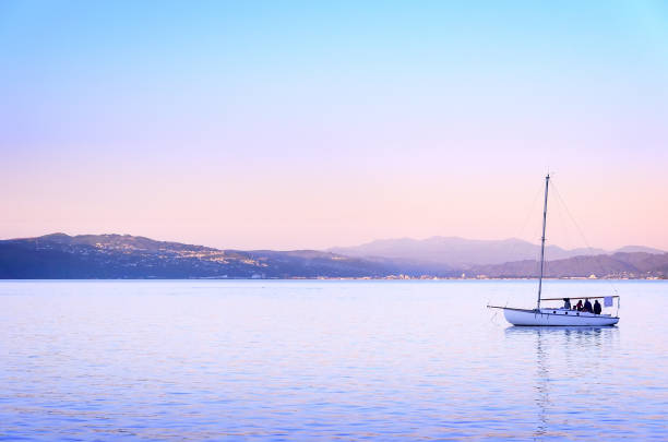 People enjoy the sunset on a sailboat in the ocean harbor in Wellington, New zealand