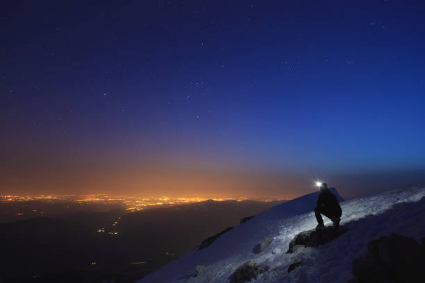 istock Climber shining a flashlight into the sky on top of a mountain 947339246