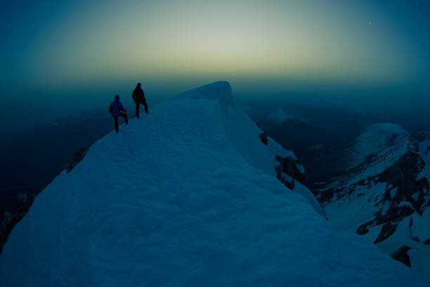 istock Two climbers on top of a mountain at night 947339380
