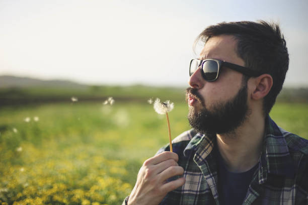 Young Man Blowing at Dandelion