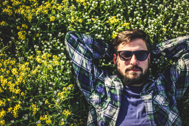 A man in a shirt with sunglasses lying in the grass