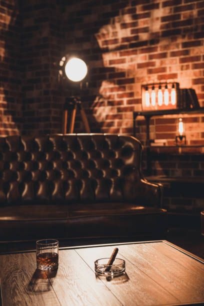 Loft interior. Leather couch with glass of whiskey and cigar on table