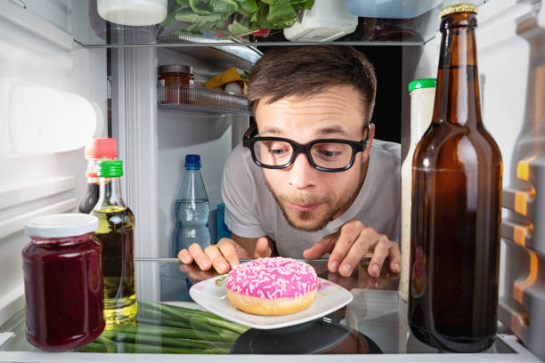 istock Man looking at a donut in the fridge 947352752
