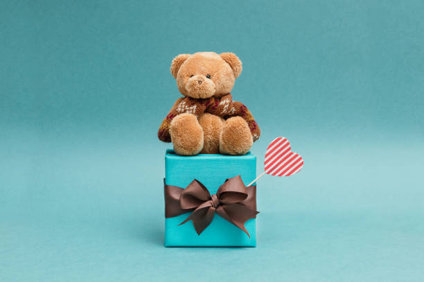 Photo of a toy teddy bear next to a Christmas tree