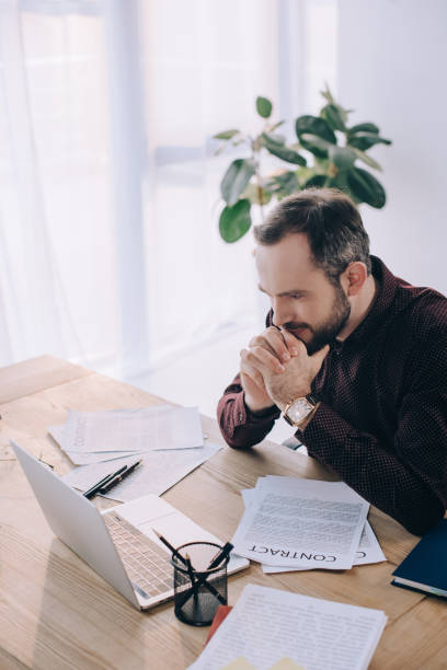 istock pensive businessman looking at laptop screen at workplace in office 947354516