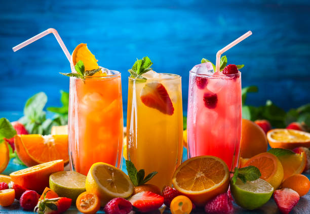 drinks Different types of summer drinks in glasses, cubes of ice and slice of fruits  on blue table. Healthy vitamin fruit and berry drinks. fruit juice stock pictures, royalty-free photos & images