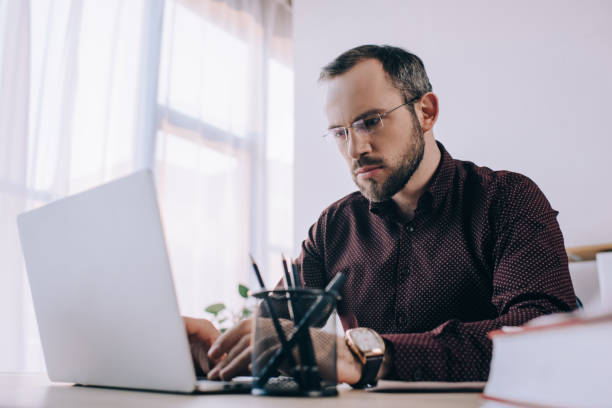 istock focused businessman in eyeglasses working on laptop at workplace in office 947356828