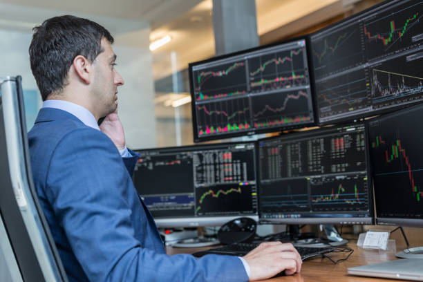 Stock broker trading online watching charts and data analyses on multiple computer screens. Male stock broker trading online watching charts and data analyses on multiple computer screens. trader stock pictures, royalty-free photos & images