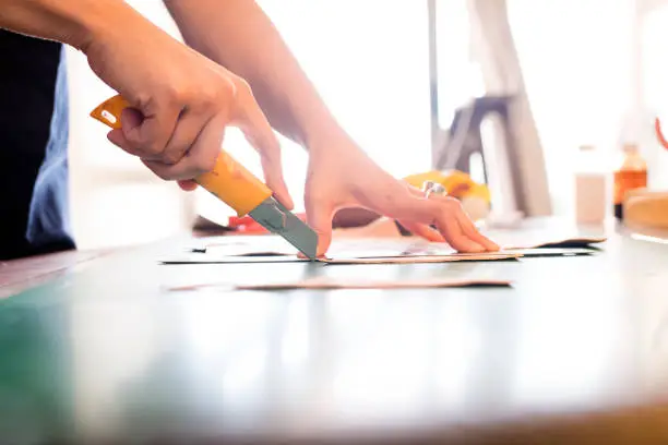 Photo of Young woman artisan cutting leather